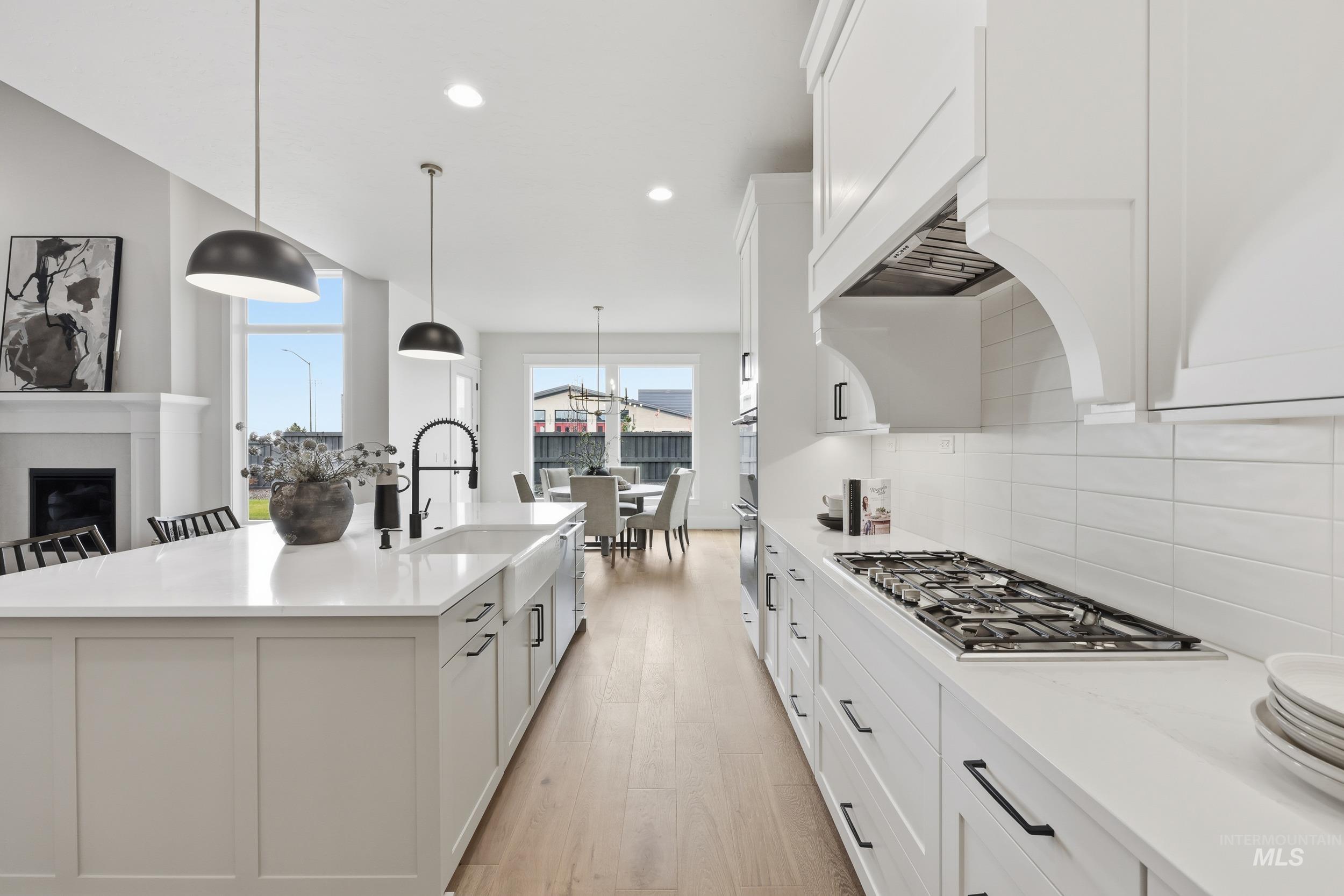 6513 South Utmost Way Meridian, ID 83642 - Photo 15 of 47 Kitchen with white cabinets, decorative backsplash, recessed lighting, a center island with sink, and pendant lighting