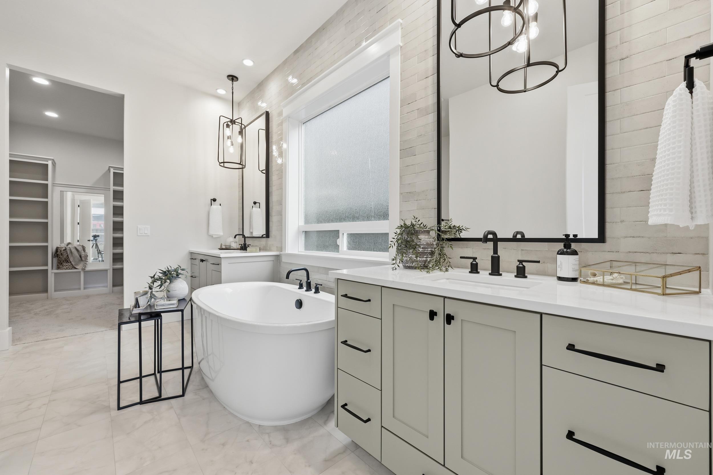 6513 South Utmost Way Meridian, ID 83642 - Photo 22 of 47 Bathroom with a spacious closet, a freestanding tub, two vanities, a chandelier, and healthy amount of natural light
