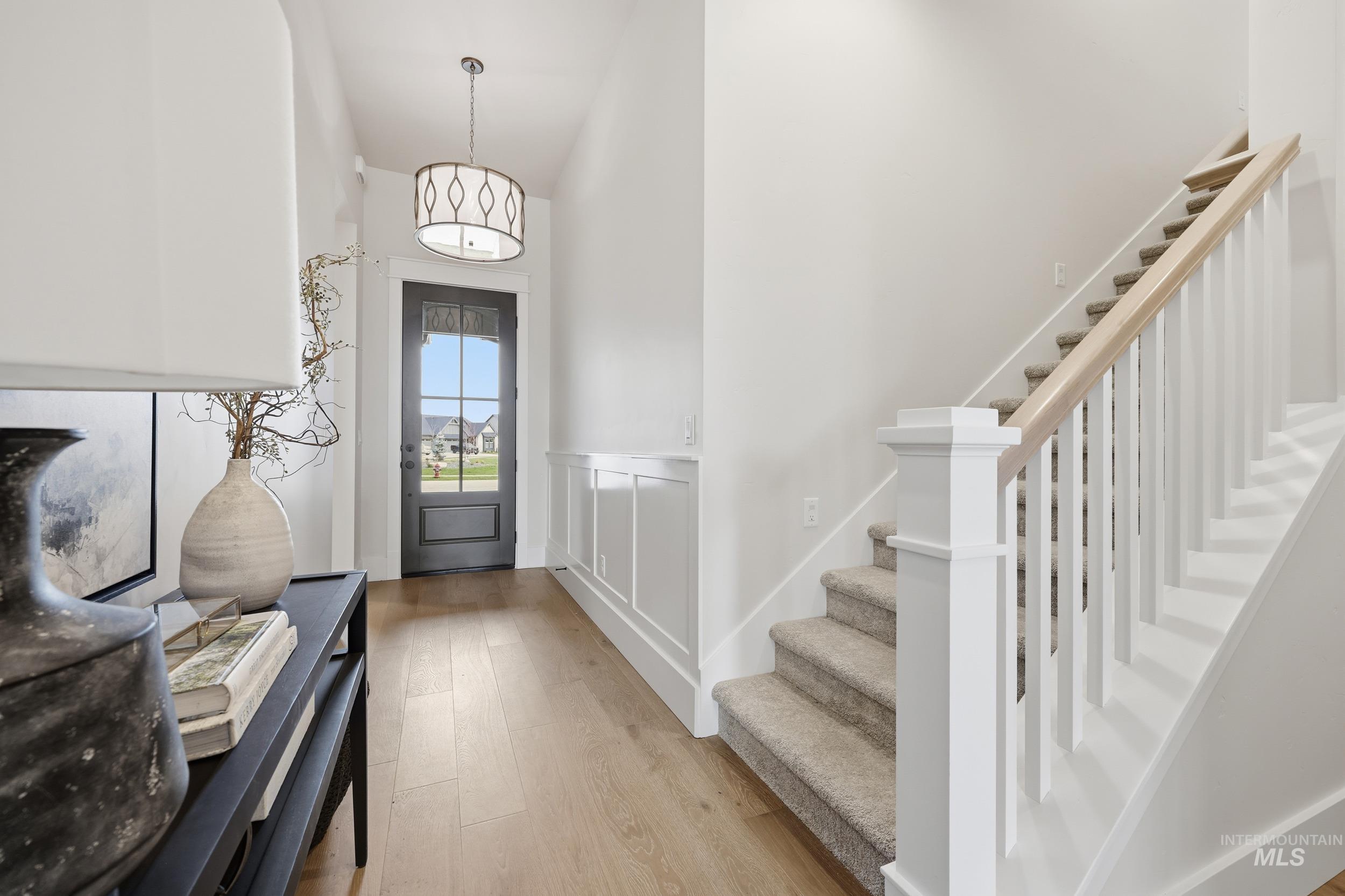 6513 South Utmost Way Meridian, ID 83642 - Photo 28 of 47 Entrance foyer featuring light wood-style floors, stairs, wainscoting, and a decorative wall