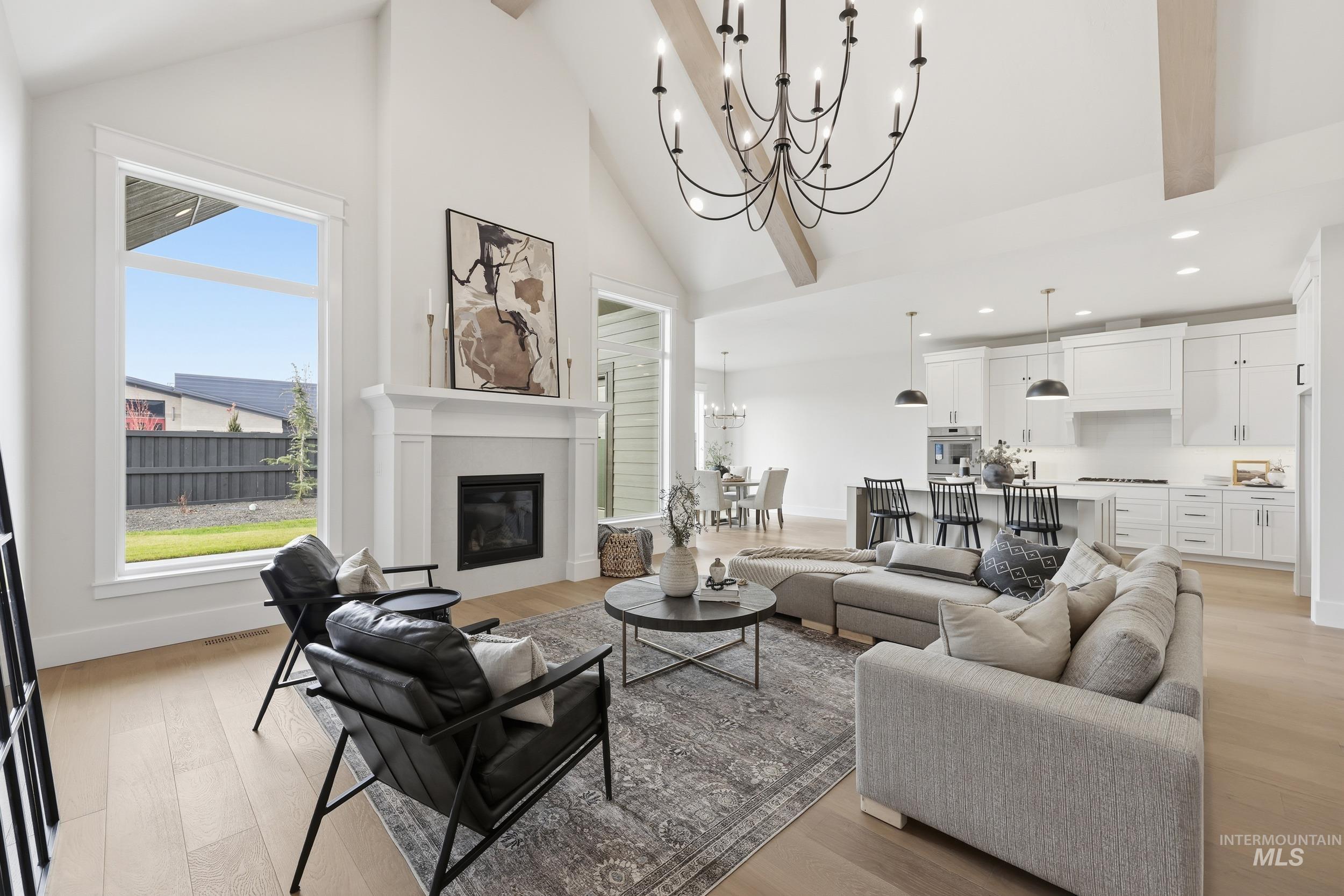 6513 South Utmost Way Meridian, ID 83642 - Photo 3 of 47 Living room with high vaulted ceiling, a chandelier, light wood-style flooring, beam ceiling, and a glass covered fireplace