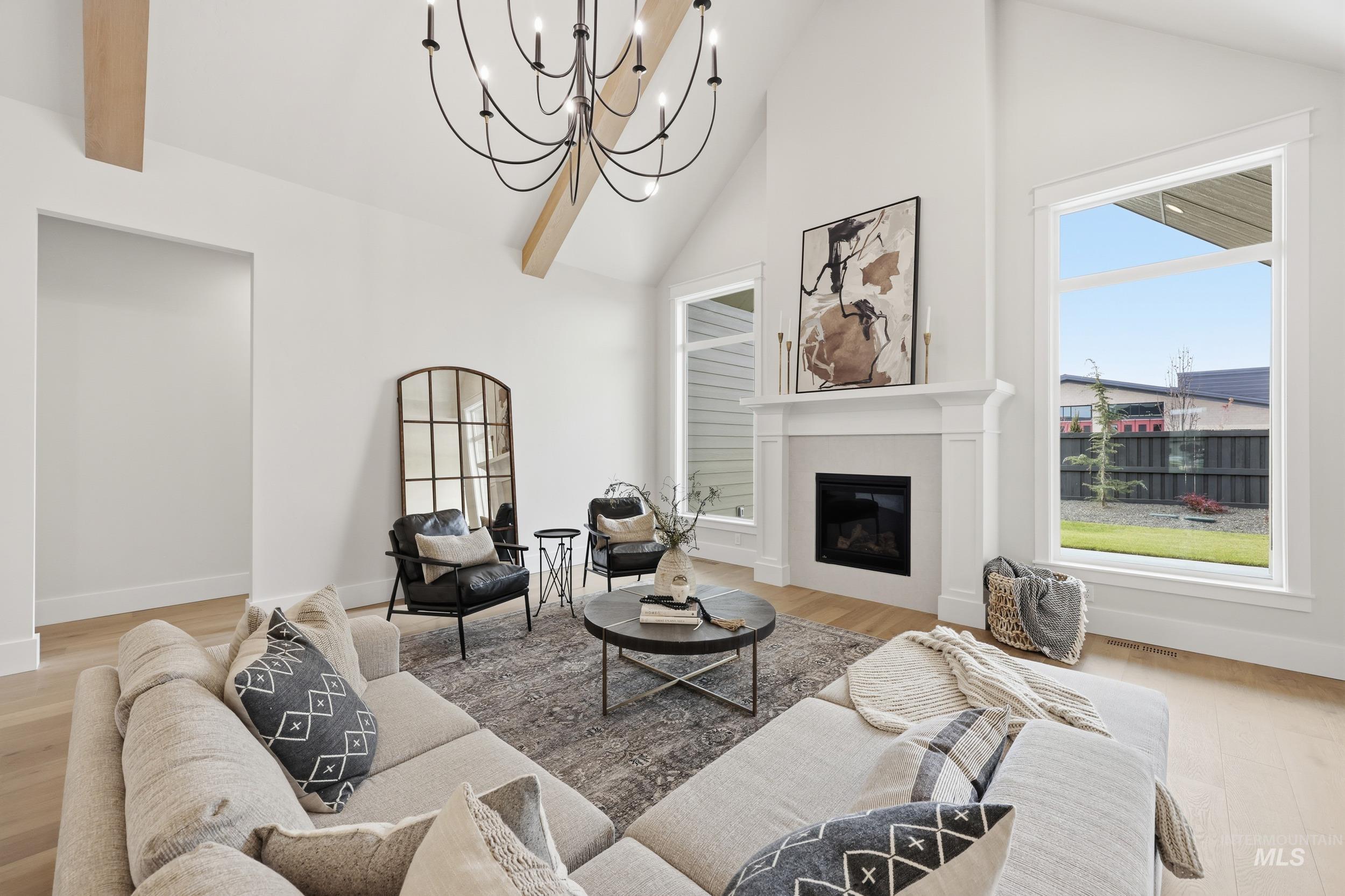 6513 South Utmost Way Meridian, ID 83642 - Photo 6 of 47 Living area featuring high vaulted ceiling, a glass covered fireplace, a chandelier, and light wood-type flooring