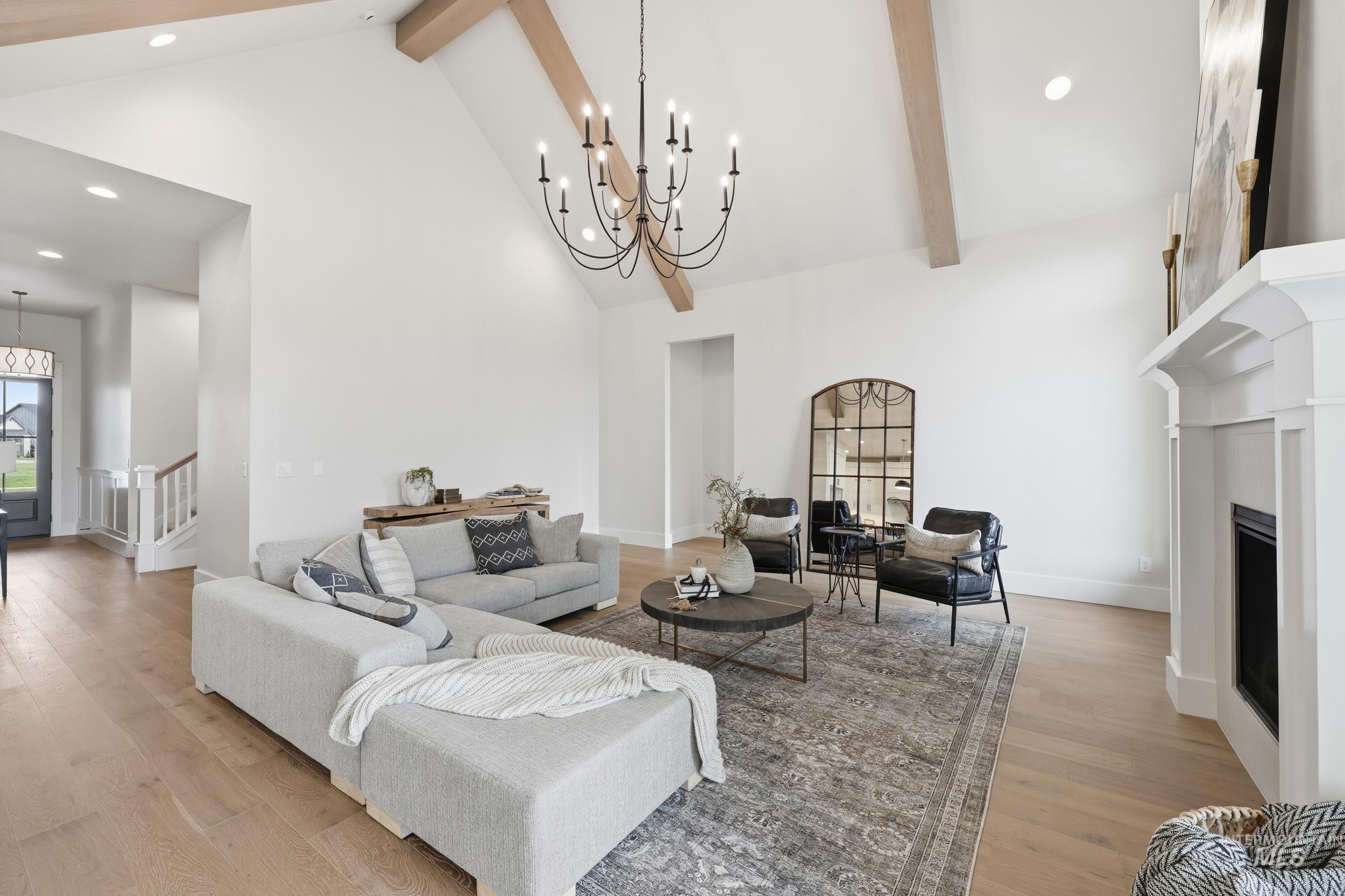 6513 South Utmost Way Meridian, ID 83642 - Photo 7 of 47 Living room featuring high vaulted ceiling, beamed ceiling, a chandelier, light wood-style floors, and a fireplace
