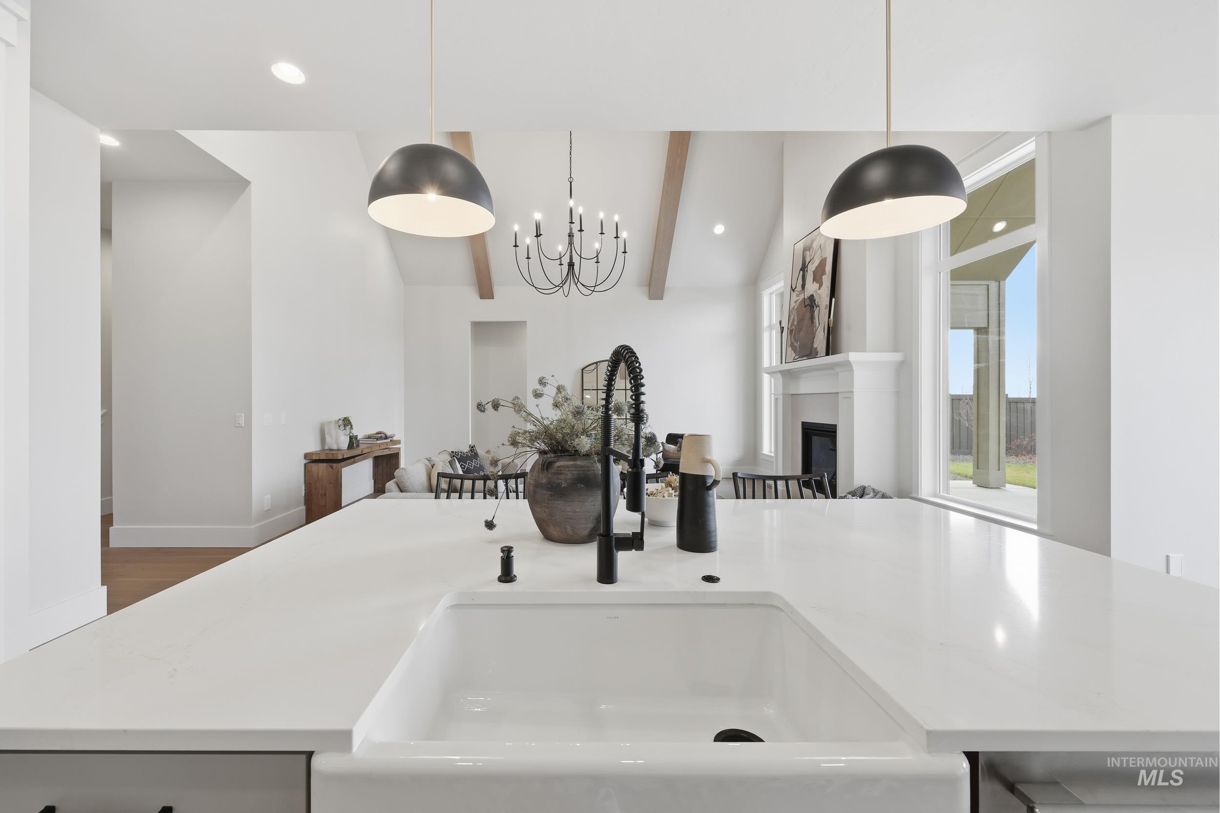 6513 South Utmost Way Meridian, ID 83642 - Photo 10 of 47 Kitchen view of a glass covered fireplace, hanging light fixtures, beamed ceiling, light stone countertops, and a chandelier