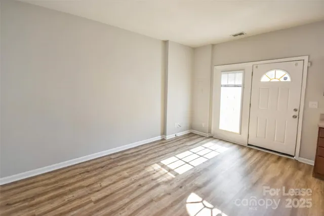 a view of an empty room and window with wooden floor