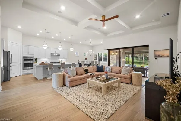 a living room with furniture kitchen view and a large window