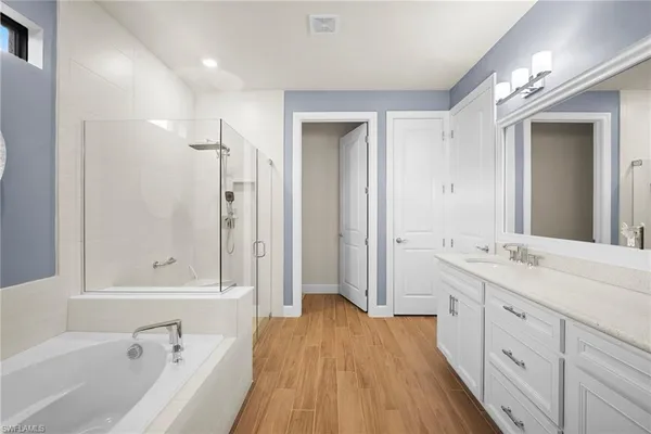 a spacious bathroom with a tub sink and mirror