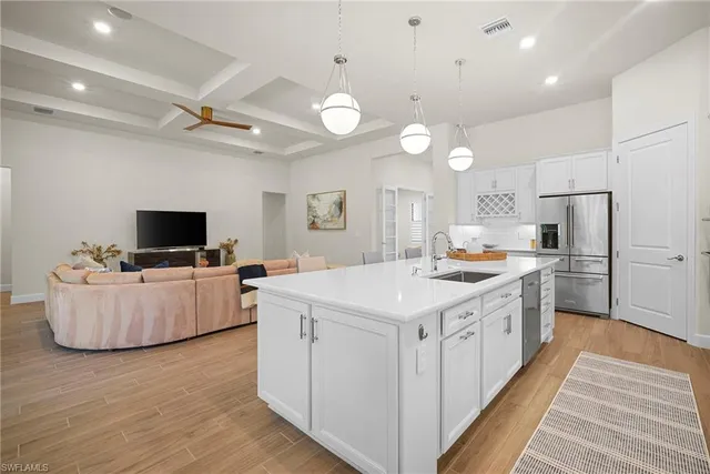 a large kitchen with kitchen island a stove a sink dishwasher a refrigerator and a dining table with wooden floor