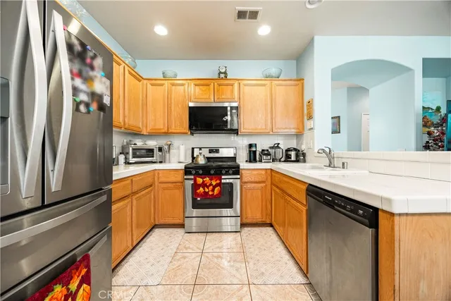 a kitchen with stainless steel appliances granite countertop a refrigerator a stove and a sink with wooden floor