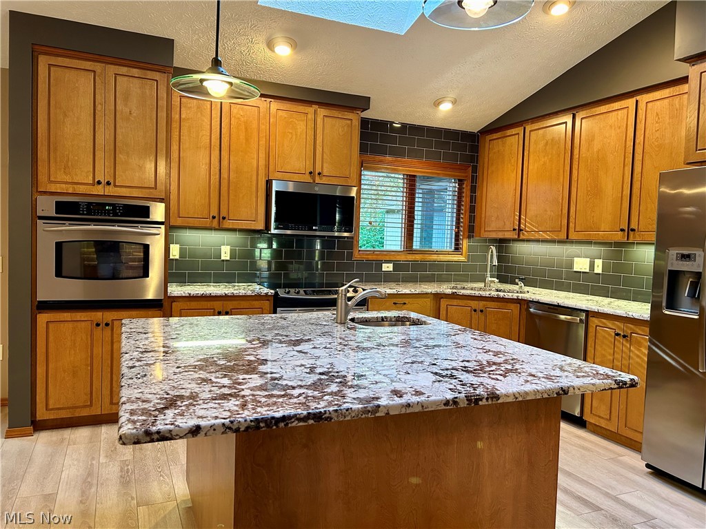 8763 Timber Edge Drive North Ridgeville, OH 44039 - Photo 4 of 40 Kitchen featuring sink, backsplash, a kitchen island with sink, and stainless steel appliances