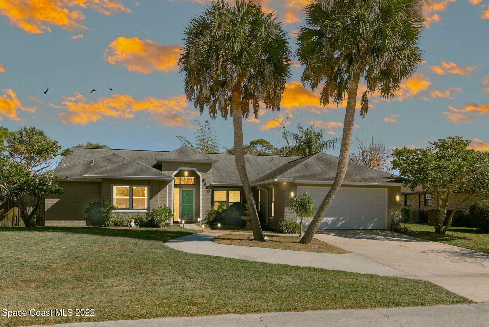 a front view of a house with a yard and potted plants
