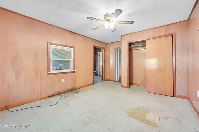 an empty room with chandelier fan and windows