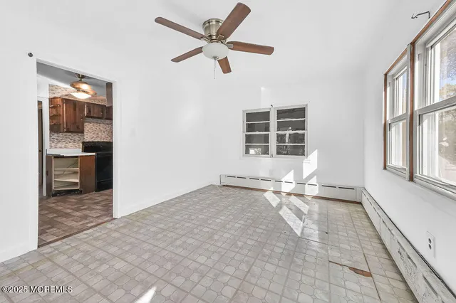 an empty room with windows and ceiling fan