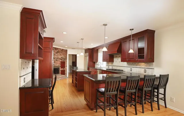 a kitchen with stainless steel appliances granite countertop a stove a sink dishwasher and a refrigerator with wooden cabinets