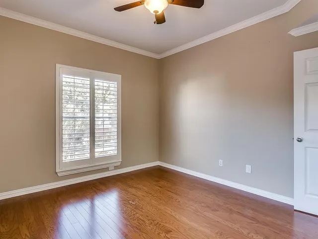 an empty room with wooden floor and a ceiling fan