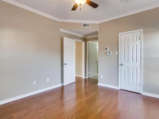 an empty room with wooden floor chandelier fan and windows