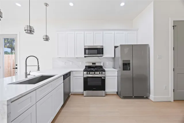 a kitchen with stainless steel appliances granite countertop a refrigerator a sink a stove and white cabinets