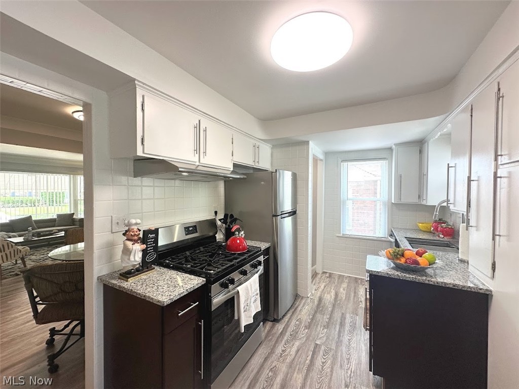 4227 Eastway Road South Euclid, OH 44121 - Photo 4 of 18 Kitchen featuring white cabinetry, light stone counters, light hardwood / wood-style floors, appliances with stainless steel finishes, and backsplash