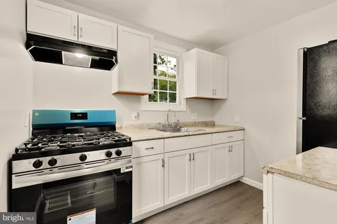 a kitchen with granite countertop a sink a stove and cabinets