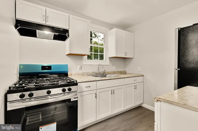 a kitchen with granite countertop a sink a stove and cabinets
