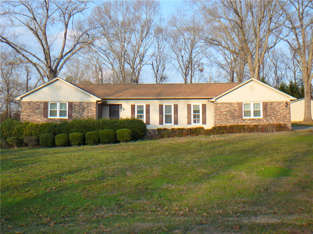 This charming home features classic brick and siding, nestled on a verdant lawn.