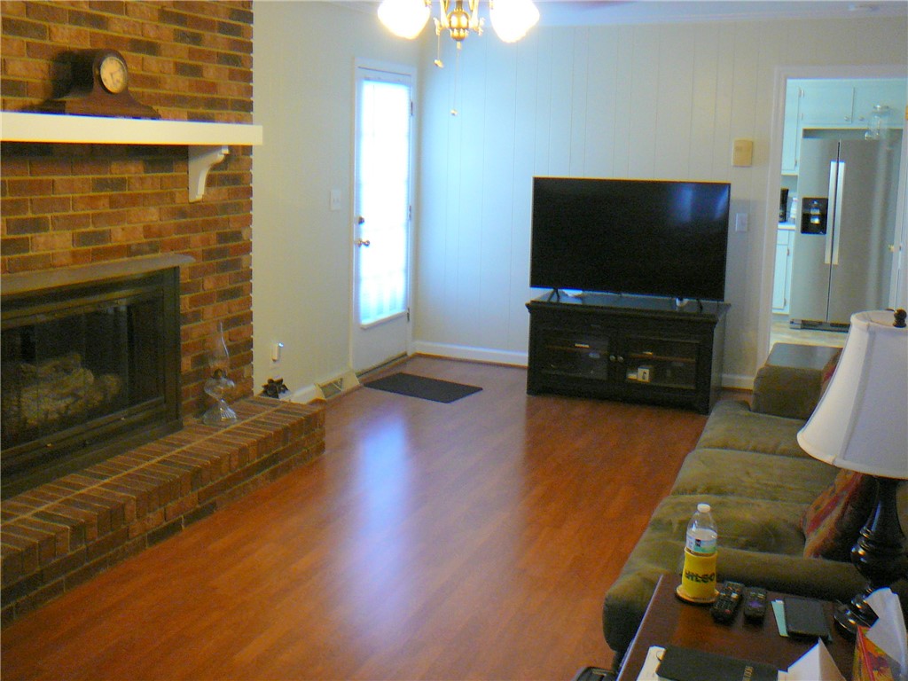 37 Camelia Circle Williamston, SC 29697 - Photo 12 of 25 This inviting living area features warm wood flooring and a classic brick fireplace, creating a cozy atmosphere.