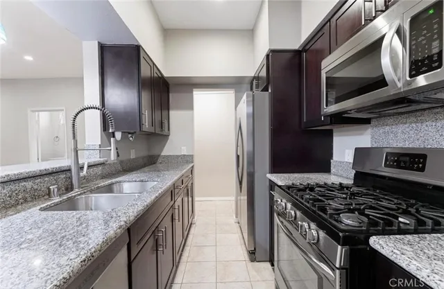 a kitchen with stainless steel appliances granite countertop a sink stove and refrigerator
