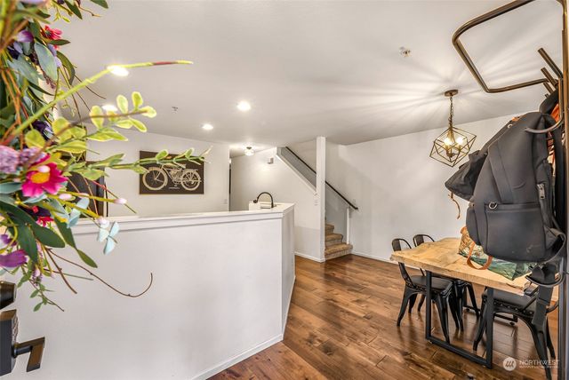 a view of a dining room and livingroom with furniture wooden floor a rug a painting and a chandelier