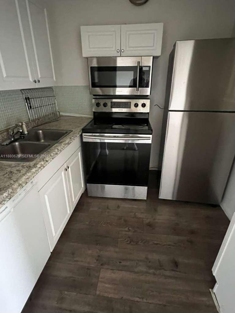 82 Fanshaw B, Unit 82 Boca Raton, FL 33434 - Photo 4 of 7 a kitchen with granite countertop a refrigerator and a stove top oven