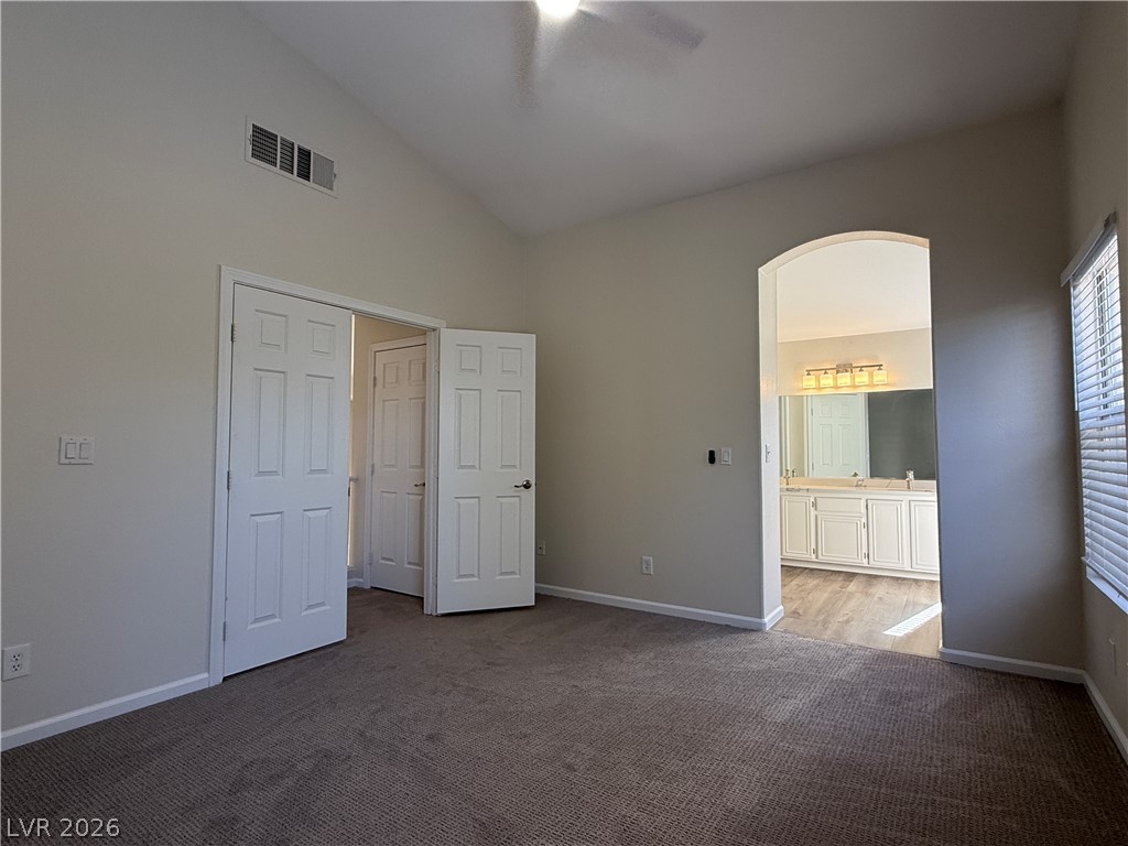 1908 Thunder Ridge Circle Henderson, NV 89012 - Photo 16 of 28 A comfortable primary bedroom with soft carpet and vaulted ceilings offers private access to a spacious vanity area.