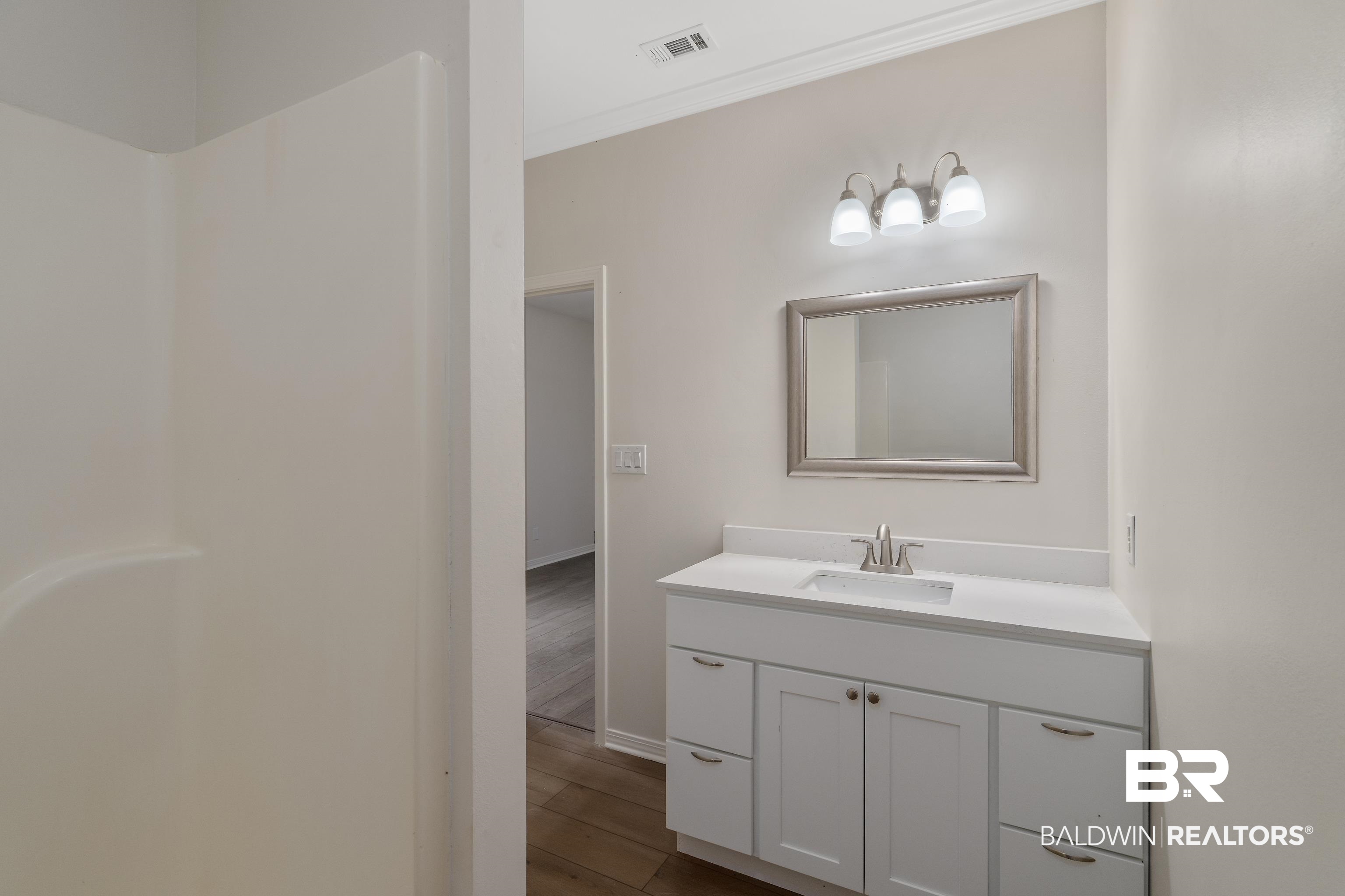 20525 Lawrence Road Fairhope, AL 36532 - Photo 16 of 26 Primary bathroom featuring vanity, crown molding, and hardwood / wood-style flooring