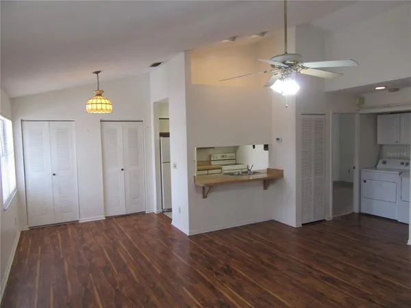 an empty room with wooden floor chandelier fan and windows
