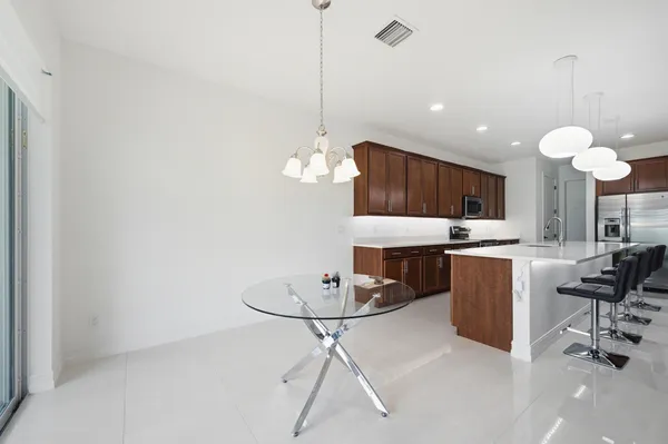 a kitchen with a refrigerator a dining table and chairs