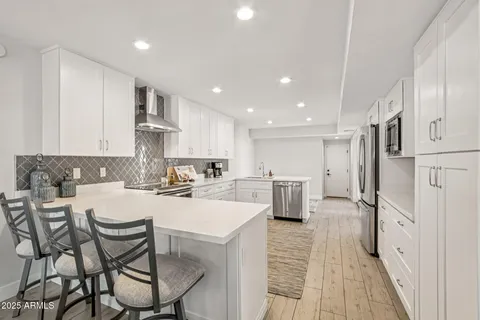 a kitchen with stainless steel appliances kitchen island granite countertop a dining table chairs and white cabinets