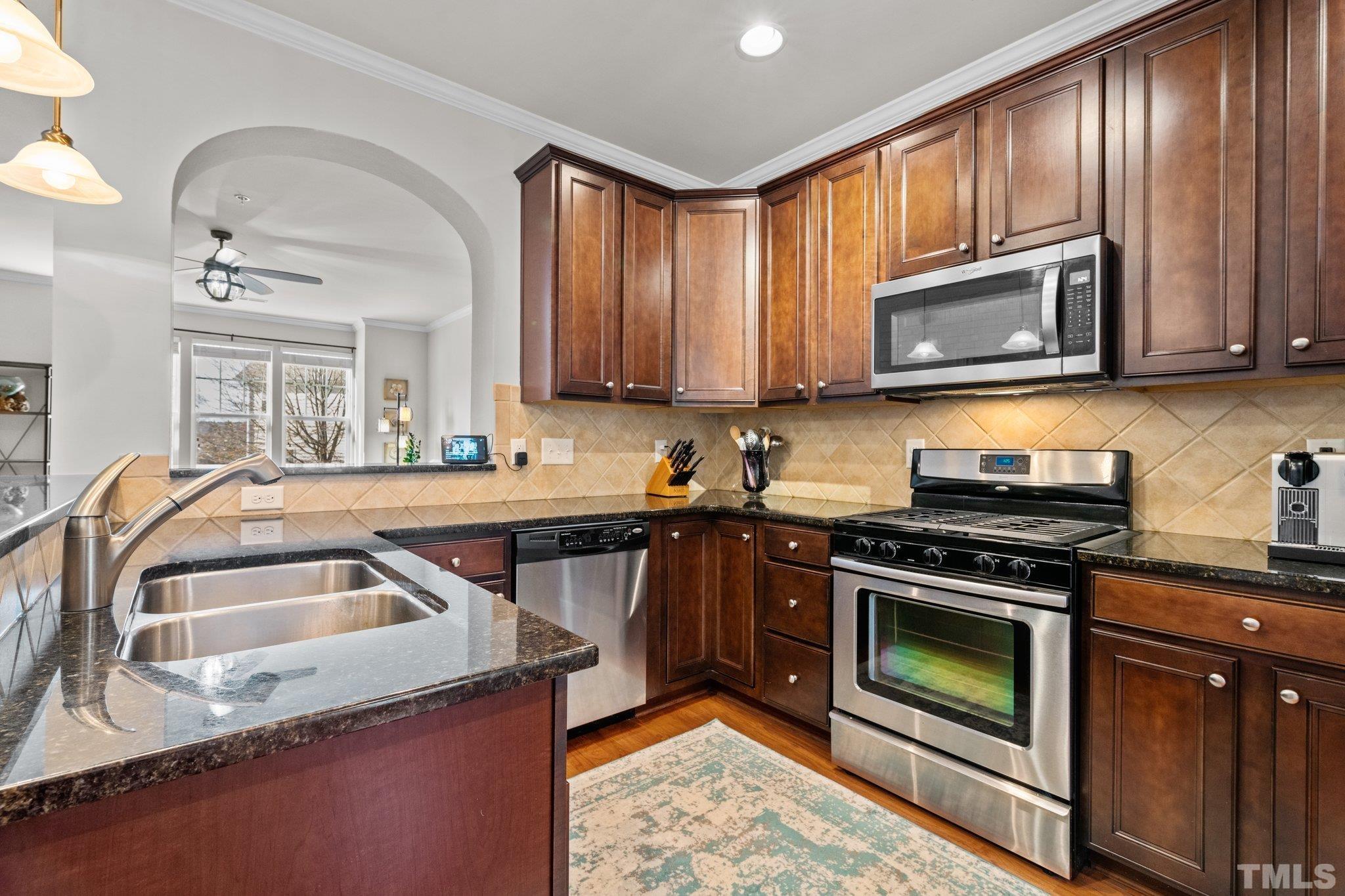 6104 Braidwood Court Raleigh, NC 27612 - Photo 15 of 31 a kitchen with granite countertop a sink a stove top oven a refrigerator cabinets and a window