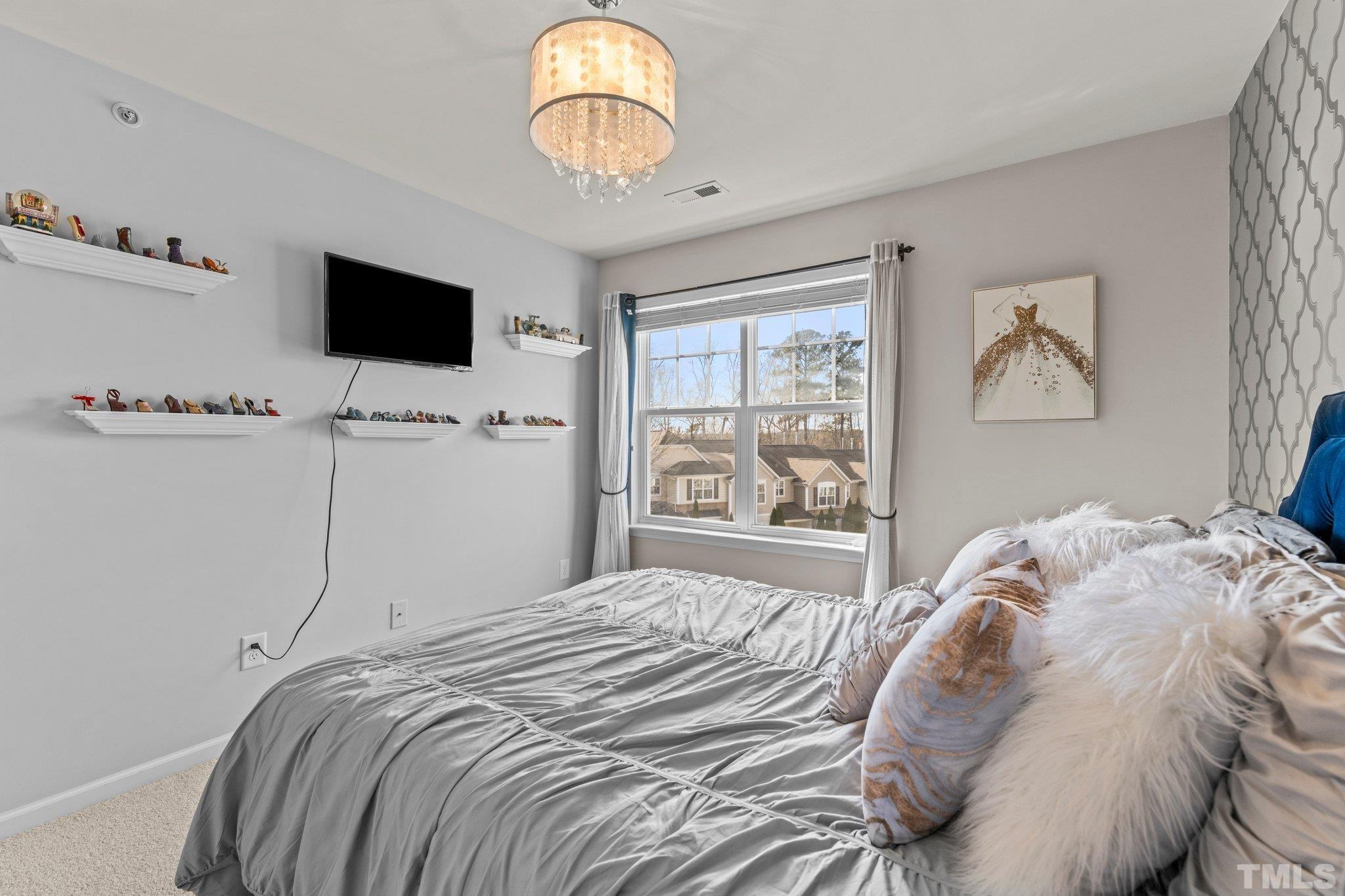 6104 Braidwood Court Raleigh, NC 27612 - Photo 20 of 31 a bedroom with a bed and a flat screen tv