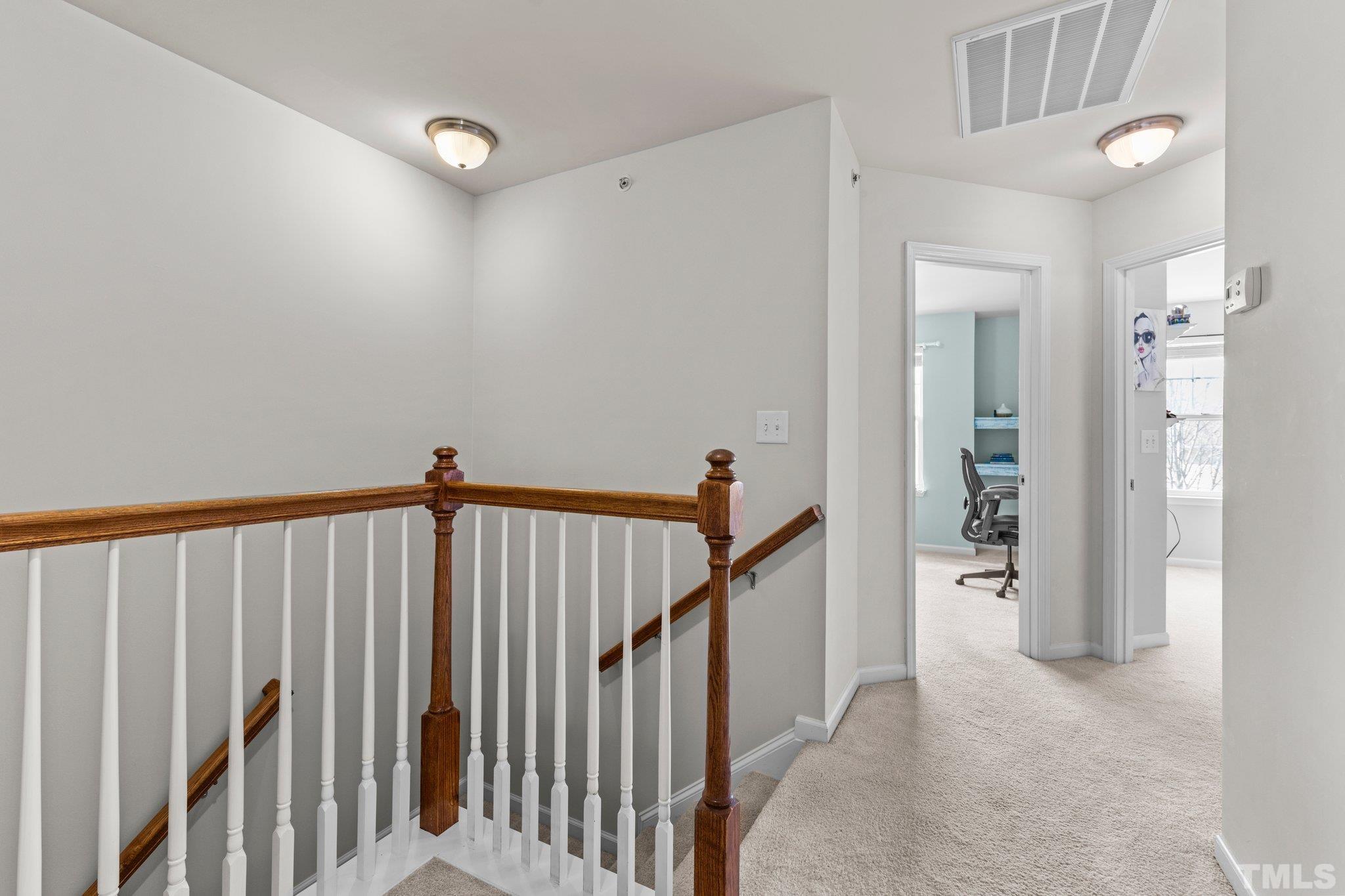 6104 Braidwood Court Raleigh, NC 27612 - Photo 22 of 31 a view of a hallway with wooden floor and staircase