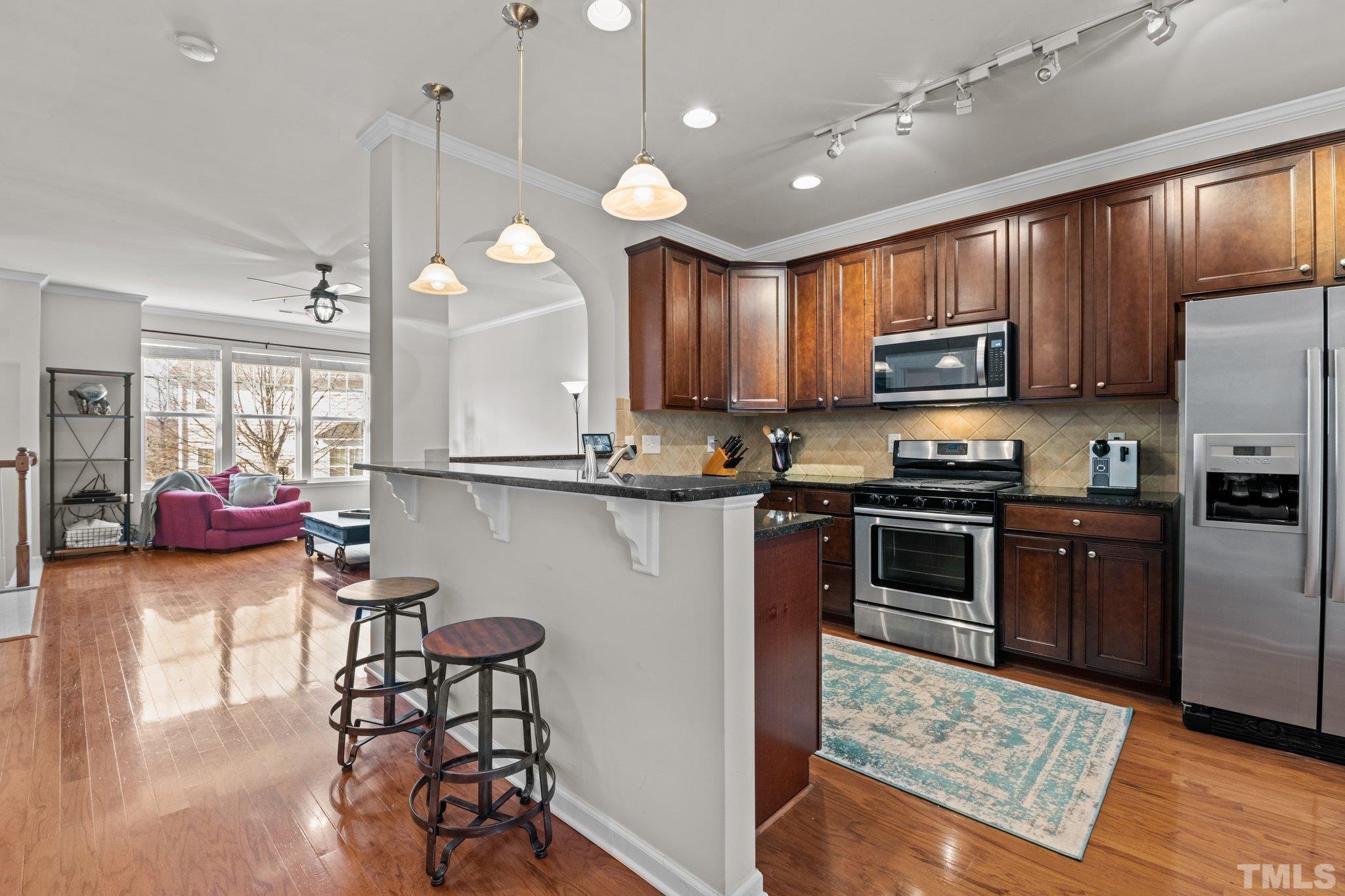 6104 Braidwood Court Raleigh, NC 27612 - Photo 5 of 31 a kitchen with kitchen island granite countertop wooden cabinets and a refrigerator
