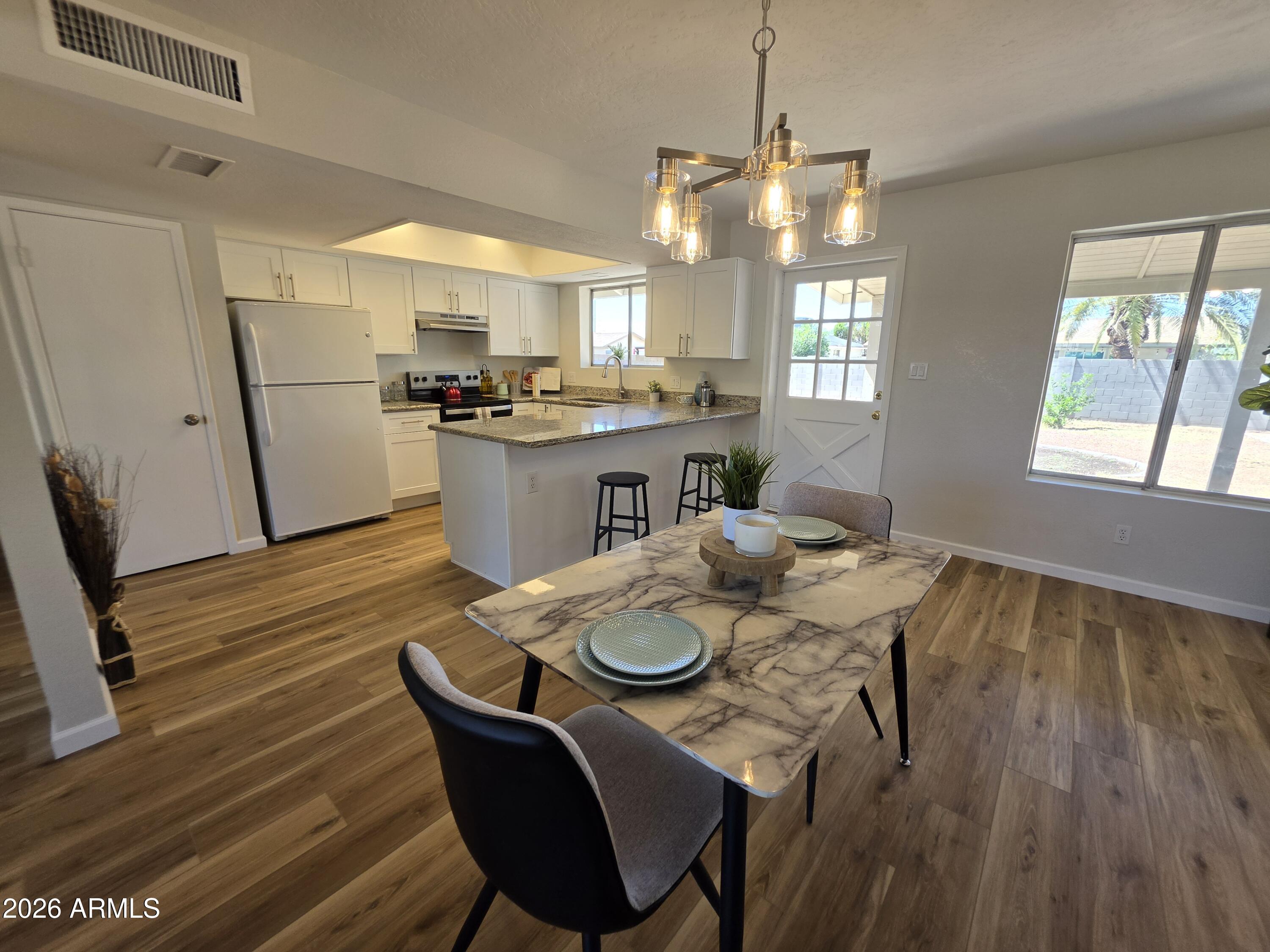 46 East McLellan Road Mesa, AZ 85201 - Photo 4 of 18 a kitchen with a table chairs refrigerator and microwave