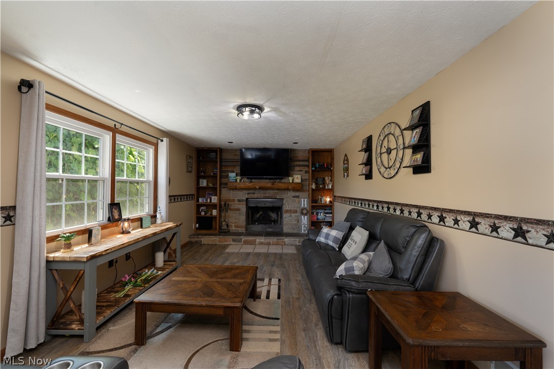 3856 Jones Road Diamond, OH 44412 - Photo 21 of 38 Living room featuring a textured ceiling, a wood burning fireplace, and luxury vinyl flooring