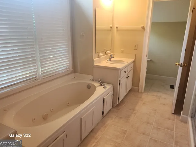 a bathroom with a tub sink and mirror