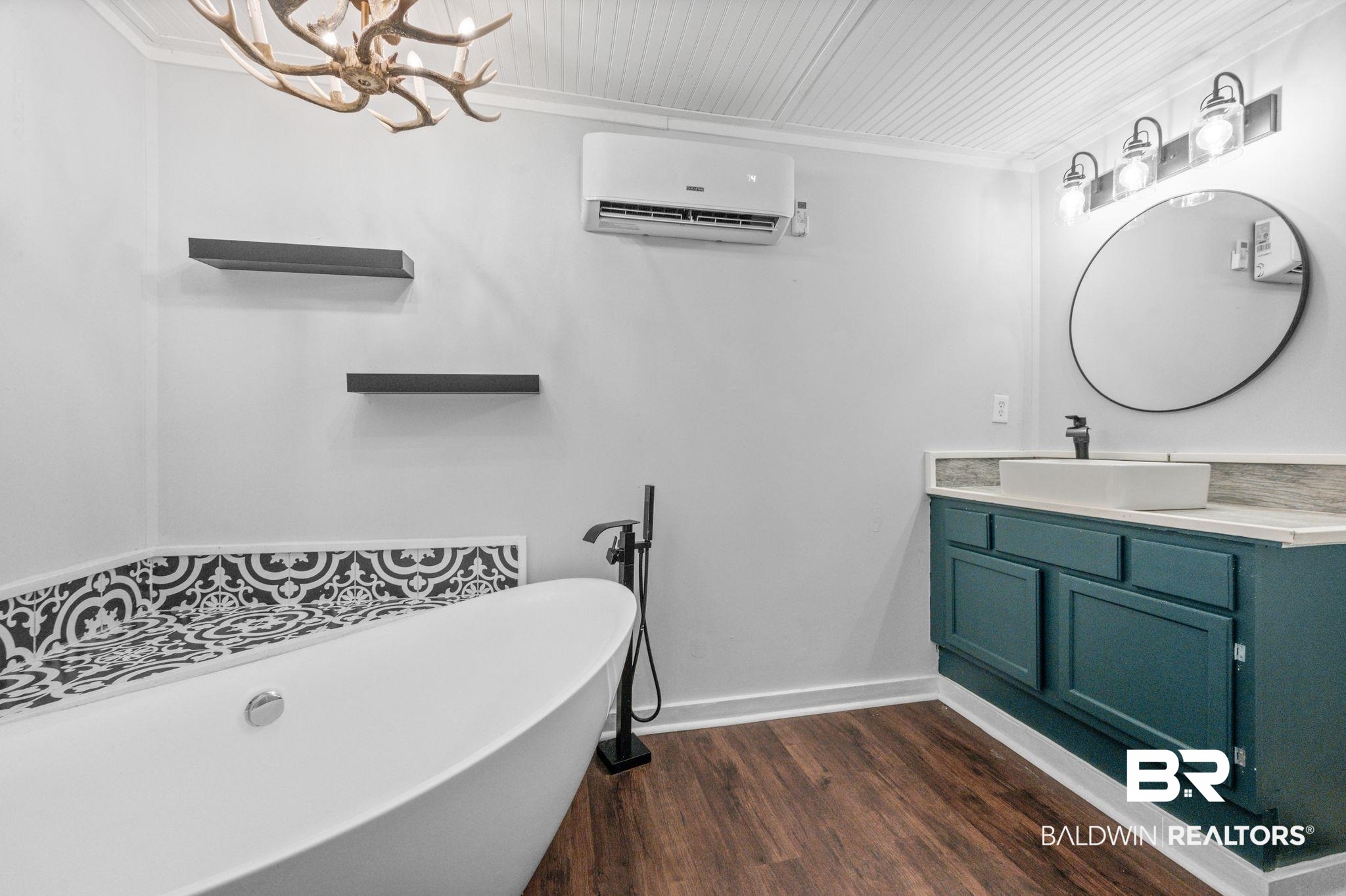 503 North Holly Street Foley, AL 36535 - Photo 13 of 23 Bathroom with a tub to relax in, wood-type flooring, a wall unit AC, vanity, and crown molding