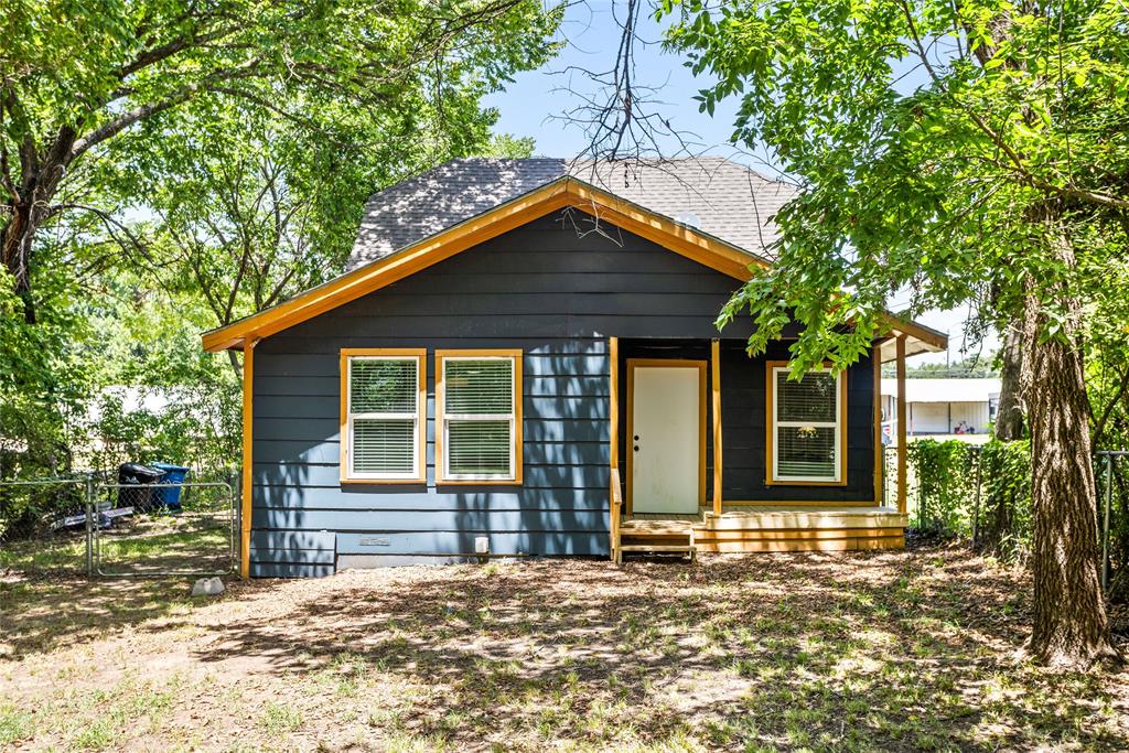 614 Rice Street Denison, TX 75020 - Photo 19 of 22 The back view of the house from the backyard. The backyard is large with trees along the perimeter. The chain link fence encloses the back yard.
