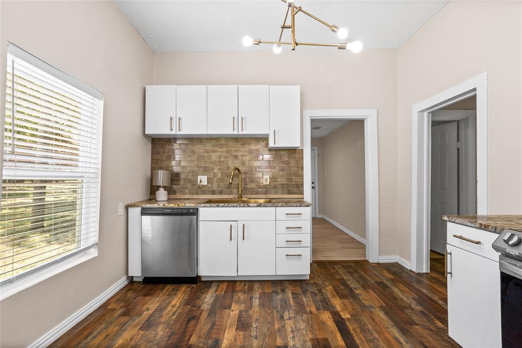 614 Rice Street Denison, TX 75020 - Photo 9 of 22 Highlighed by a large window for natural light, a large kitchen and updated cabinets along with stainless steel appliances highlight this lovely kitchen area.