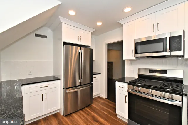 a kitchen with granite countertop a sink a stove and cabinets
