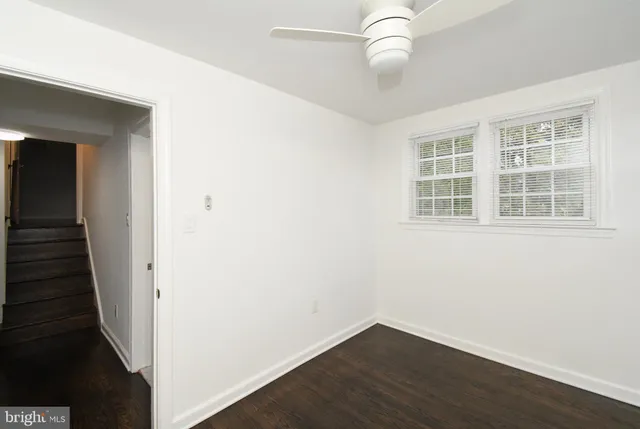 an empty room with wooden floor chandelier fan and windows