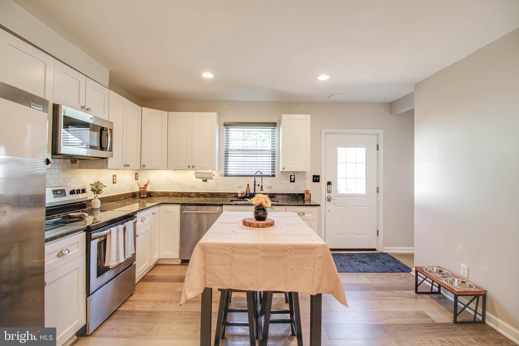 7805 Outing Avenue Pasadena, MD 21122 - Photo 9 of 51 a kitchen with sink a stove and chairs