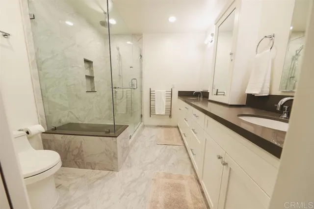 a bathroom with a granite countertop sink a toilet and shower