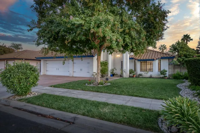 a front view of a house with a yard and a garden