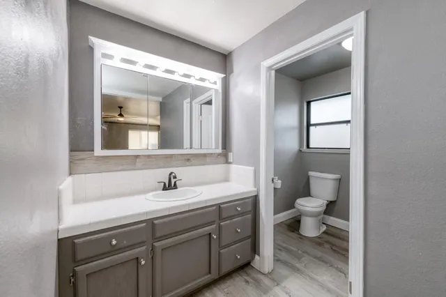 an empty room with wooden floor ceiling fan and windows