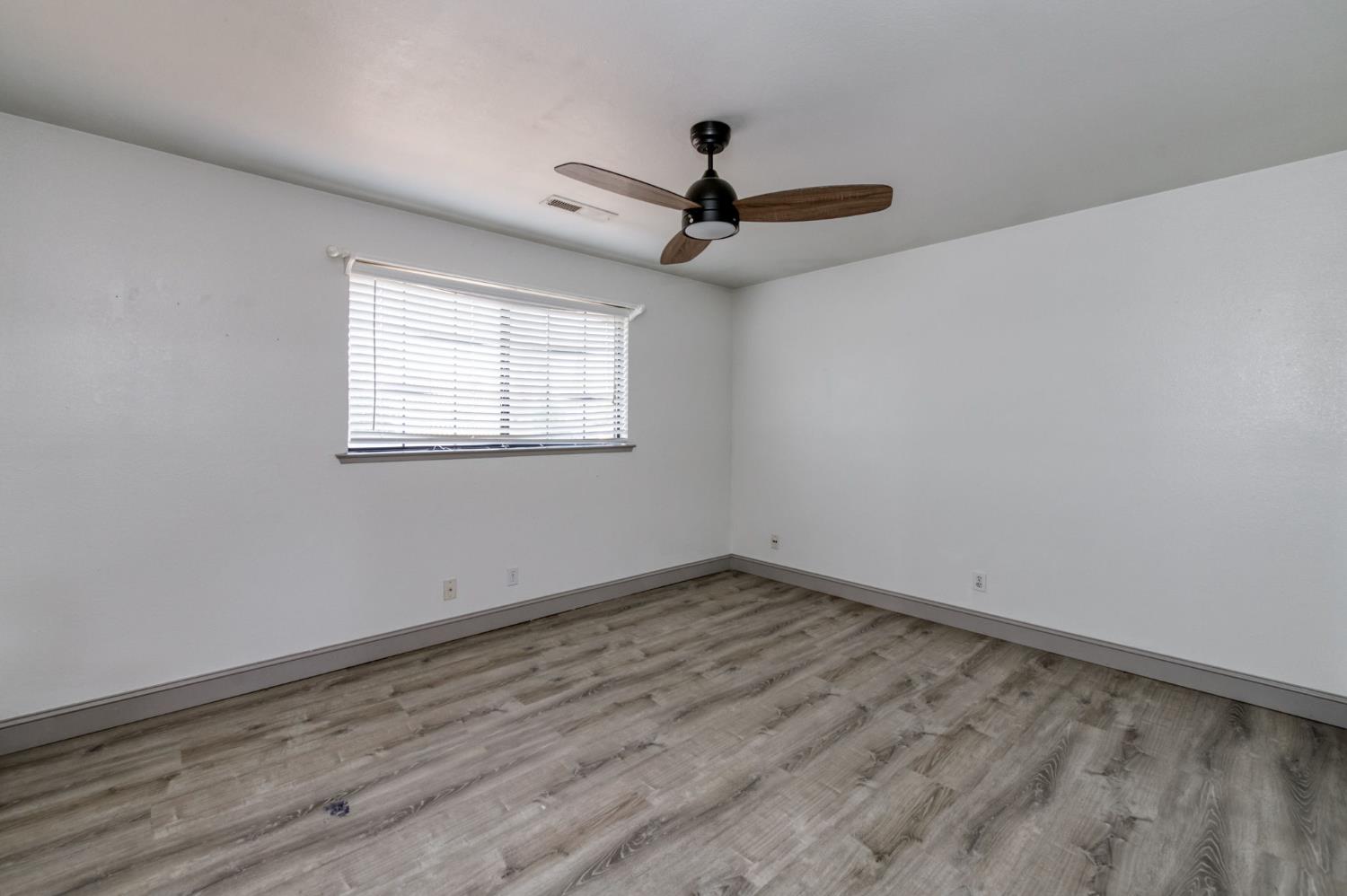 3040 Boulder Avenue Madera, CA 93637 - Photo 29 of 50 an empty room with wooden floor ceiling fan and windows